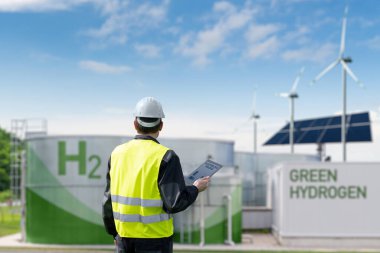 Engineer with tablet computer on a background of Green Hydrogen factory. High quality photo clipart