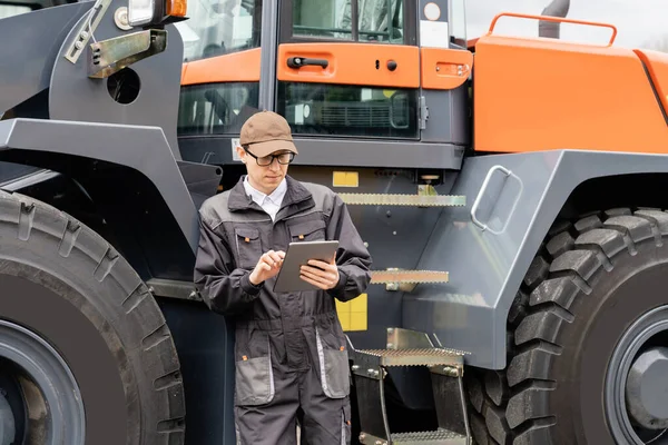 Serviceman Con Tableta Digital Fondo Del Tractor Foto Alta Calidad — Foto de Stock