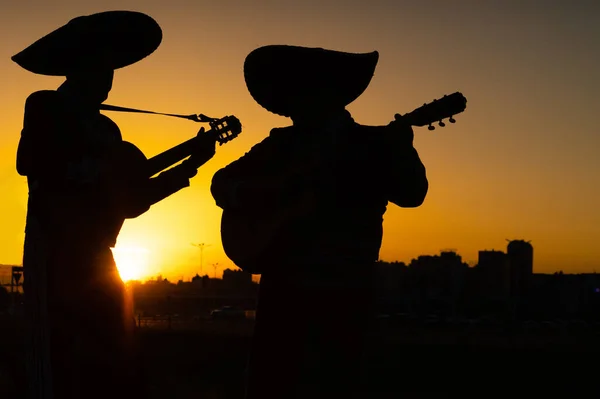 都市のパノラマの背景にメキシコのミュージシャンマリアーチバンドのシルエット — ストック写真
