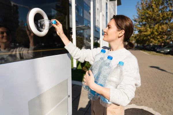 妇女在城市街道上使用自助服务机接收用过的塑料瓶和塑料罐 — 图库照片