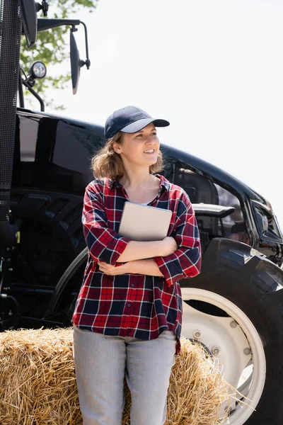 拥有数字平板电脑的女农民 背景是一辆农用拖拉机 — 图库照片