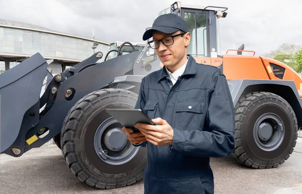 トラクターの背景にデジタルタブレットを持つサービスマン — ストック写真