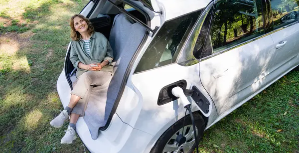 Vrouw Met Smartphone Zit Kofferbak Van Een Elektrische Auto — Stockfoto