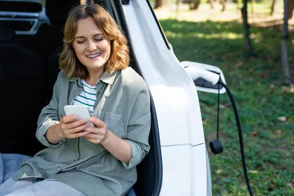 Wanita Dengan Smartphone Duduk Bagasi Mobil Listrik — Stok Foto