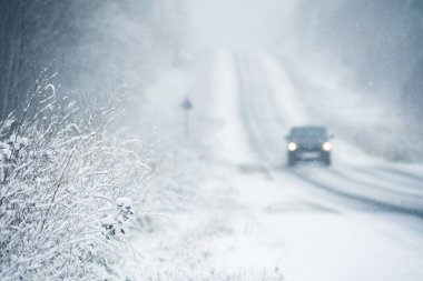 The car is driving on a winter road in a blizzard. Focus on foreground. clipart