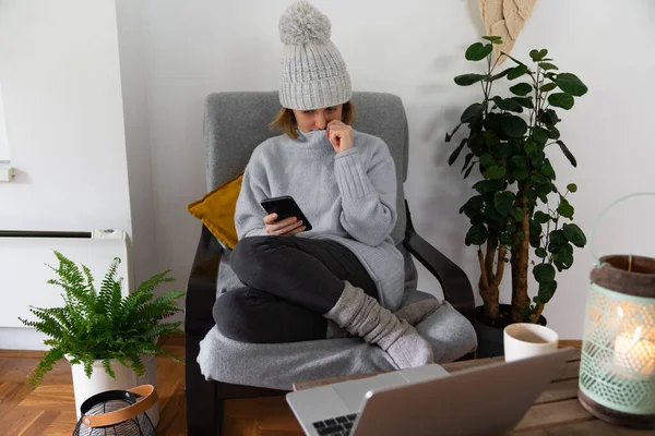 Eine Frau Warmer Kleidung Mit Smartphone Sitzt Neben Einem Heizkörper — Stockfoto