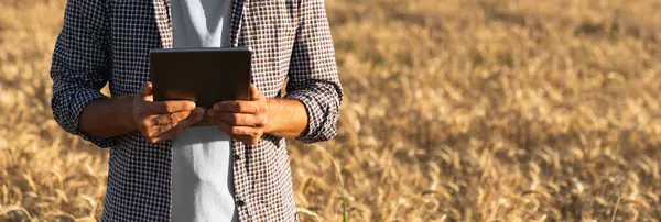 Farmer with digital tablet on an agricultural field. Close up. Smart farming and digital agriculture..