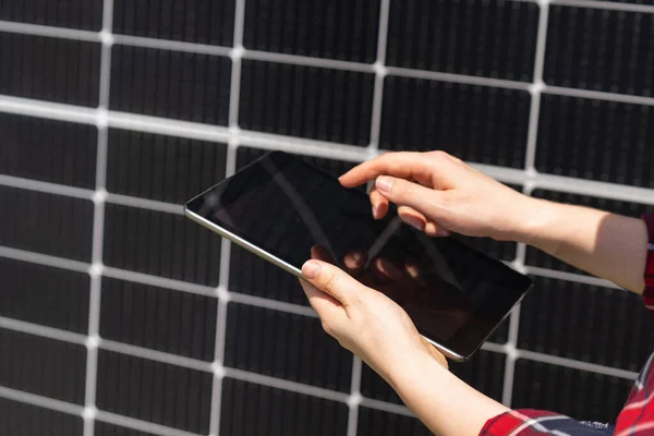Hands with digital tablet on a background of solar panels.