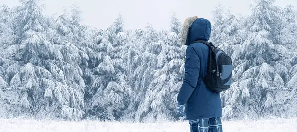雪景下 穿着蓝色外套 头戴毛皮帽 背着背包的旅客的背景图 — 图库照片