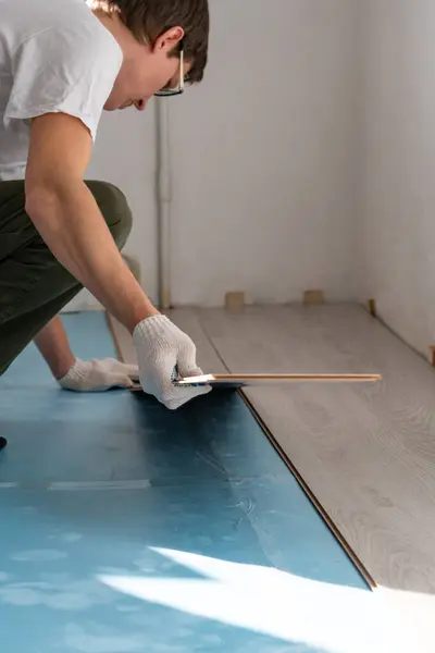 Man is repairing the floor in the house, laminate flooring..