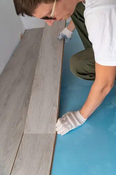 Man is repairing the floor in the house, laminate flooring..