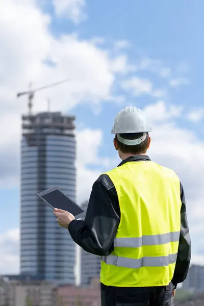 Engineer with a digital tablet on the background of a building under construction.