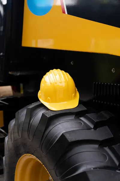 A yellow hard hat lies on the wheel of a construction machine.