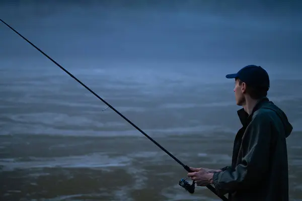 夜に山の川で釣る男 — ストック写真