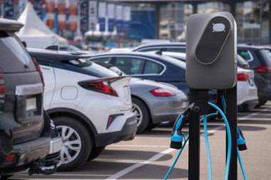 Electric vehicles charging station on a background of a row of cars. Concept.. clipart