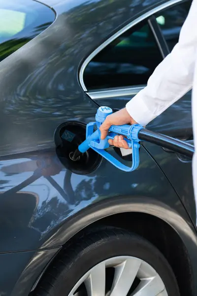 Man holds a hydrogen fueling nozzle. Refueling car with hydrogen fuel. Concept..