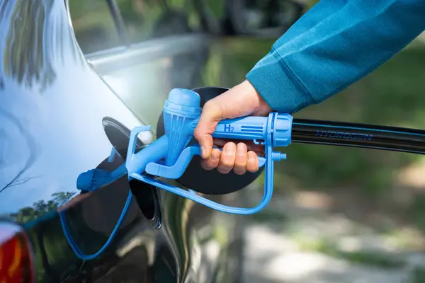 Man holds a hydrogen fueling nozzle. Refueling car with hydrogen fuel. Concept..