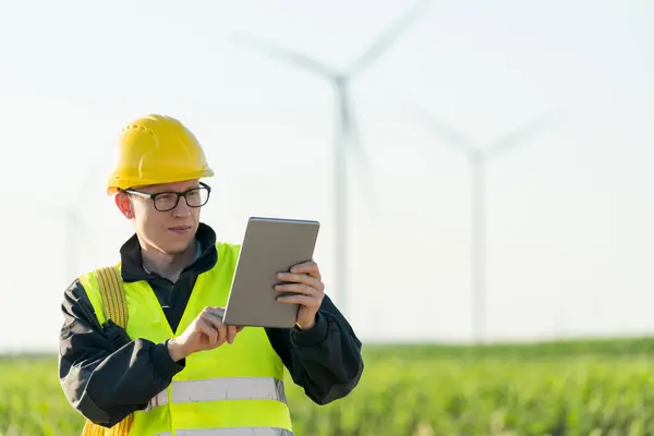 stock image Engineer with digital tablet works on a field of wind turbines.