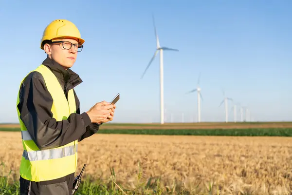 stock image Engineer with digital tablet works on a field of wind turbines.