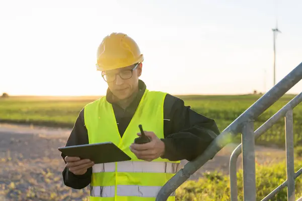 stock image Engineer with digital tablet controls wind turbines.