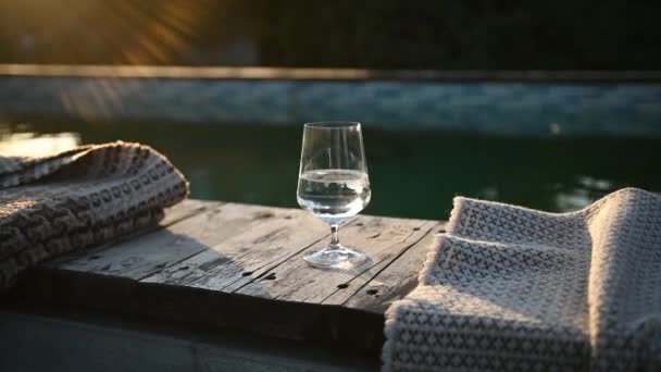 日没時にはワインのグラスがプールのそばに立っている 隣に毛布があります いい秋の日 — ストック動画