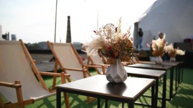 Masanın üzerinde kurumuş çiçeklerle dekoratif bir vazo var. Çatıda dinlenmek için güzel bir yaz yeri.