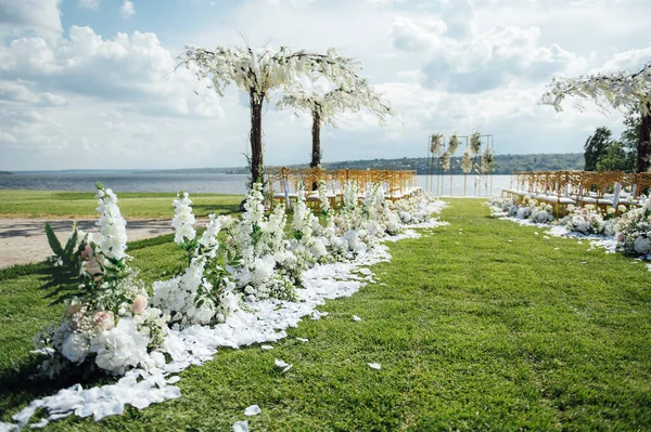藤の木と川の岸に新婚旅行の結婚式のためのプレミアムアーチ 空の椅子と傘 ロイヤリティフリーのストック写真