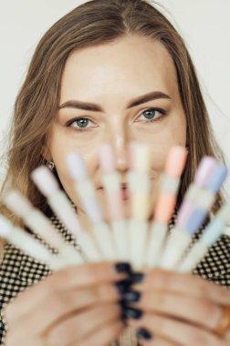 Professional woman master of manicure posing with samples of nails.