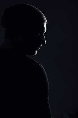 Siyahi stüdyonun arka planında dikilirken ciddi bir dramatik adam başka tarafa bakıyor..