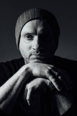 Siyahi stüdyonun arka planında dikilirken ciddi bir dramatik adam gözlerini kaçırıyor. Siyah beyaz fotoğraf