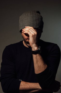 Siyahi stüdyonun arka planında dikilirken ciddi bir dramatik adam başka tarafa bakıyor..