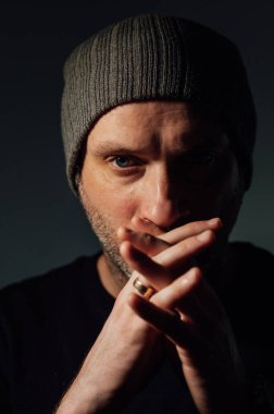 Siyahi stüdyonun arka planında dikilirken ciddi bir dramatik adam başka tarafa bakıyor..