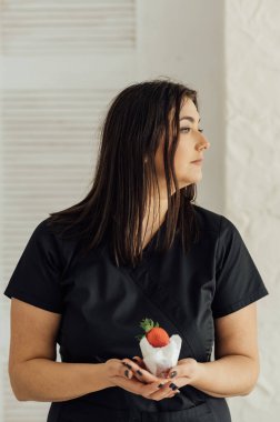 çilek ve krema ile lezzetli pasta yemeye kadar parlak yapmak ile genç ve güzel esmer kadın portresi kadar yakın.