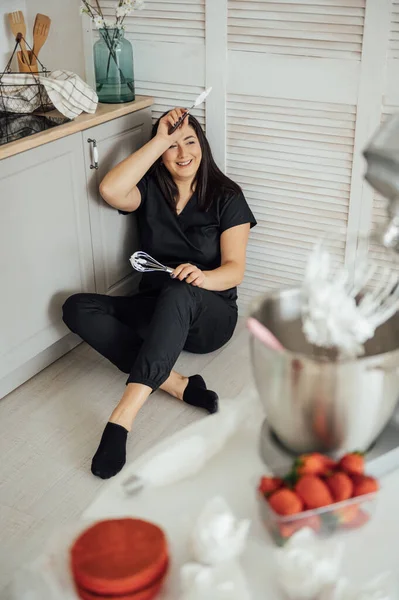 stock image Woman cook sits on the floor against the background of a blender. Tired of a lot of orders