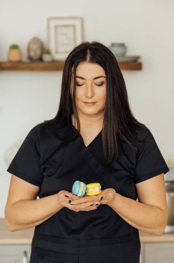 Şekerci elinde iki tane sarı ve mavi Fransız makaronu tutuyor. Ukrayna bayrak renkleri.