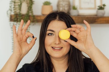 Gülümseyen kadın gözlerini kapayan lezzetli, renkli bir makarna tutuyor..