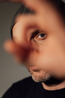 Siyahi stüdyonun arka planında dikilirken ciddi bir dramatik adam başka tarafa bakıyor..