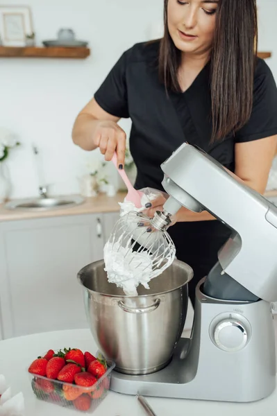 The girl cook puts the cream from the mixer into the mold for decorating cakes.