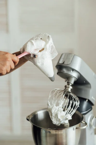 The girl cook puts the cream from the mixer into the mold for decorating cakes.