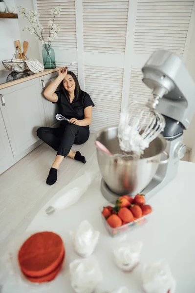 stock image Woman cook sits on the floor against the background of a blender. Tired of a lot of orders