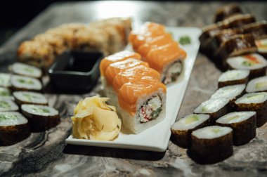 Lezzetli suşi ruloları, wasabi, zencefil ve soya sosu siyah gri masada..