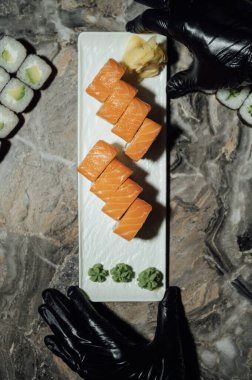 Lezzetli Philadelphia suşi ruloları, wasabi, zencefil ve soya sosu siyah gri bir masada..