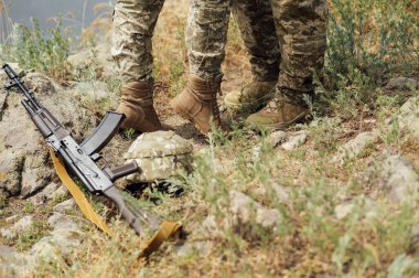 Otomatik silahların yanında bir erkek ve bir kadının bacakları. Ukrayna ordusu. Ukrayna askerleri. Askeri üniforma..