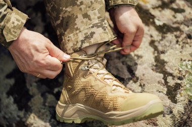 Ayakkabı bağcığı bağlayan Ukraynalı bir asker. Yaz tatili. Piksel desenli üniforma.