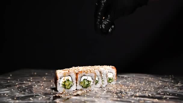 日本の伝統的な食べ物である寿司やロールにゴマを振りかける手料理 王室エビ アボカド クリームチーズ ゴマで寿司をロール — ストック動画