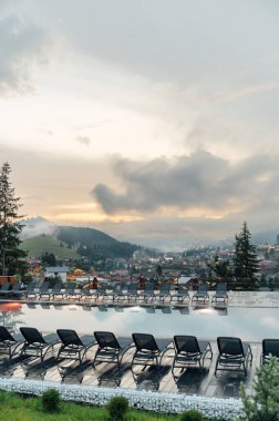 Ukrayna 'daki otellerden birinde bir yüzme havuzu. Karpat Dağları, akşam vakti, gün batımı ve bulutlar.