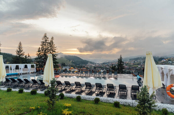 Бассейн в одном из отелей Украины. Карпатские горы, вечернее время, закат и облака.