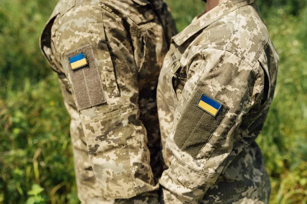 Armed Forces of Ukraine. Married couple in military uniform with a pixel pattern hold hands. Ukraine flag patch on the shoulder. The struggle for the independence of the country