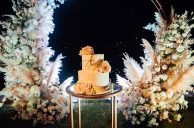 Çiçekli güzel düğün pastası ve büyük bir düğün kemeri.