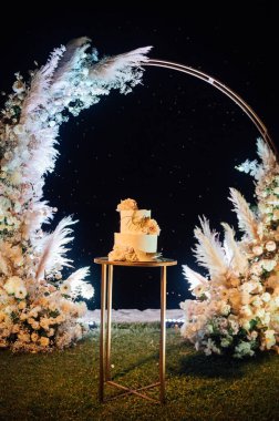 Çiçekli güzel düğün pastası ve büyük bir düğün kemeri.